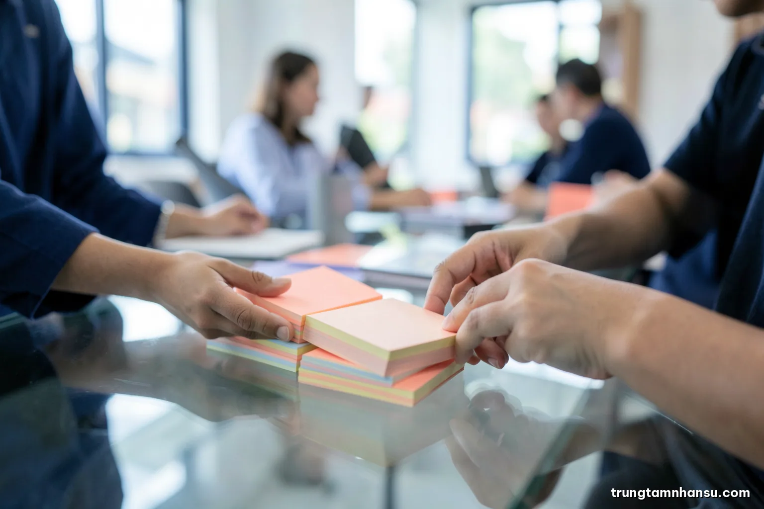 Close-up of two hands comparing stacks of blank colored sticky notes on a glass table in a bright Saigon office, shallow depth of field, cool grey and coral tones